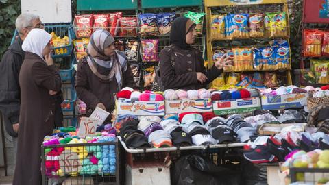 Man sieht ein Geschäft in Damaskus mit Wolle, Kleidung und Chipstüten.