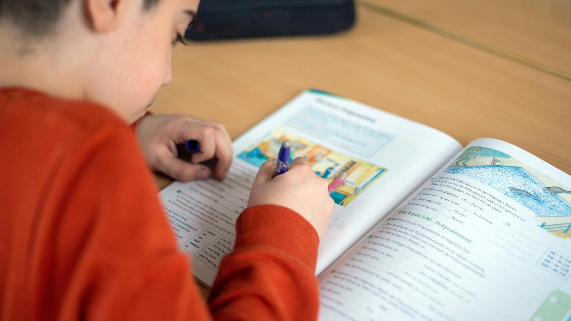 Ein Schüler schreibt während des Unterrichts in einer Grundschule in einem Schulbuch. Ein Schüler schreibt während des Unterrichts in einer Grundschule in einem Schulbuch.
