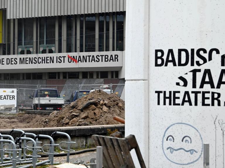 Am Badischen Staatstheater ist der Schriftzug "Die Würde des Menschen ist unantastbar" angebracht. Die Buchstaben UN wurden mit roter Farbe durchgestrichen.