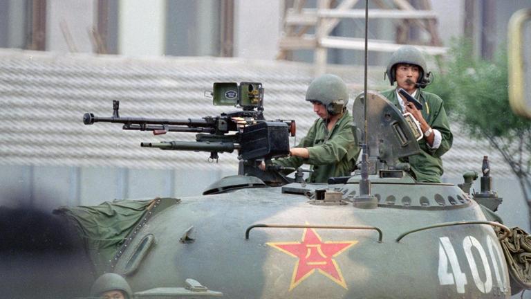 Zwei Soldaten der Volksbefreiungsarmee mit Geschützen auf der Oberfläche eines Panzers 1989 in Peking.