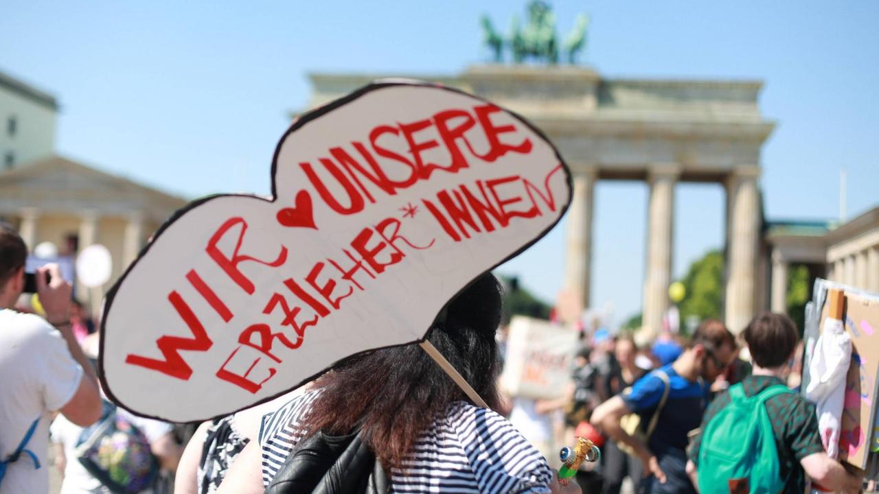 "Wir lieben unsere Erzieher" steht auf dem Plakat einer Demonstrantin vor dem Brandenburger Tor in Berlin "Wir lieben unsere Erzieher" steht auf dem Plakat einer Demonstrantin vor dem Brandenburger Tor in Berlin