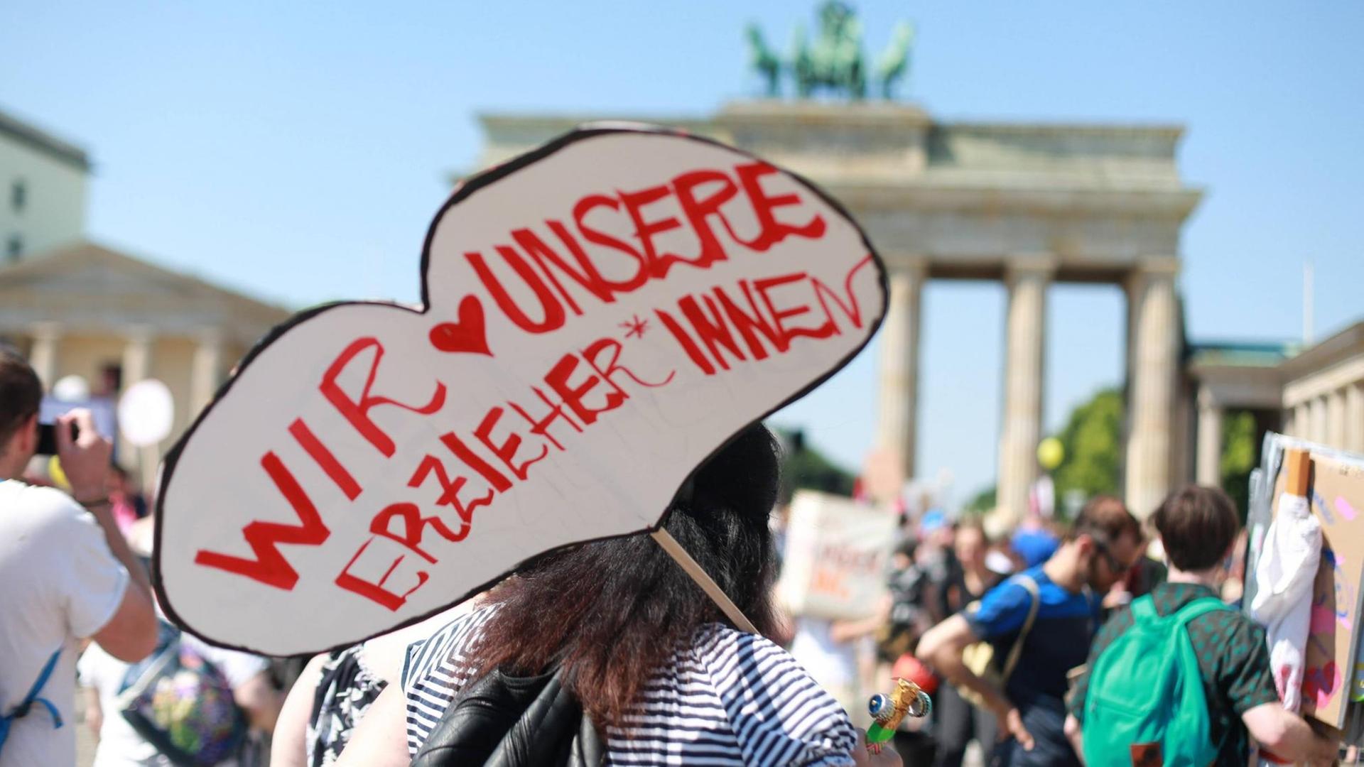 "Wir lieben unsere Erzieher" steht auf dem Plakat einer Demonstrantin vor dem Brandenburger Tor in Berlin "Wir lieben unsere Erzieher" steht auf dem Plakat einer Demonstrantin vor dem Brandenburger Tor in Berlin