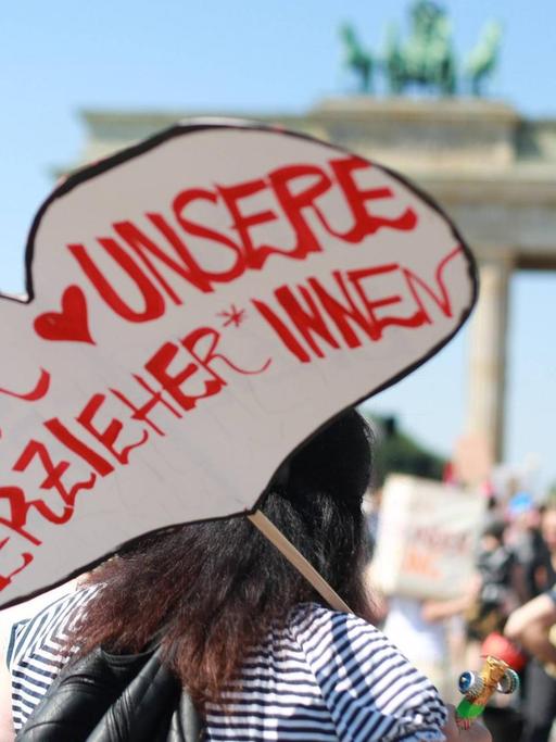 "Wir lieben unsere Erzieher" steht auf dem Plakat einer Demonstrantin vor dem Brandenburger Tor in Berlin