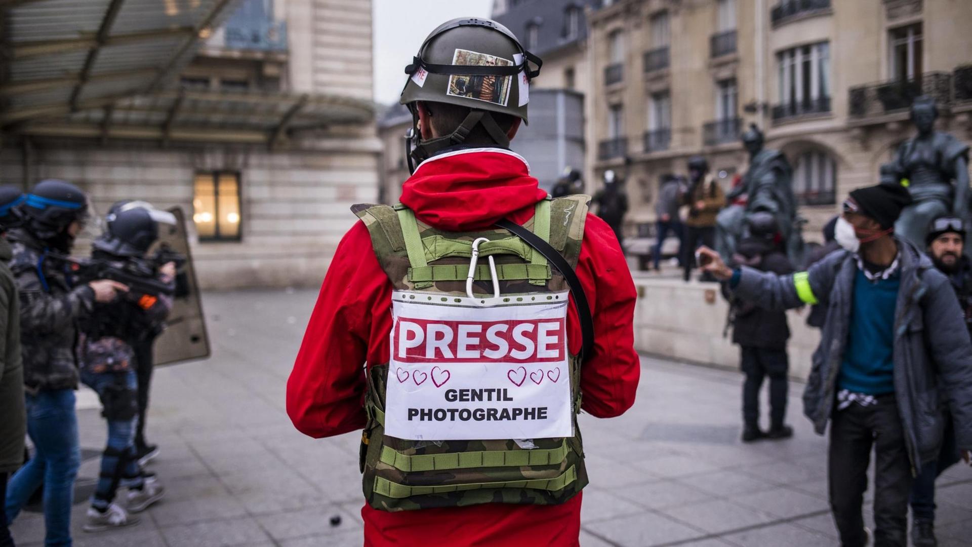 Ein Journalist in Paris trägt bei den Gelbwesten-Protesten ein Schild mit der Nachricht "Presse - freundlicher Fotograf" auf dem Rücken. Ein Journalist in Paris trägt bei den Gelbwesten-Protesten ein Schild mit der Nachricht "Presse - freundlicher Fotograf" auf dem Rücken.