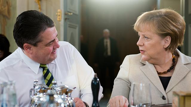 Bundeskanzlerin Angela Merkel (CDU) und Wirtschaftsminister Sigmar Gabriel (SPD) sitzen an einem Tisch und schauen sich an.