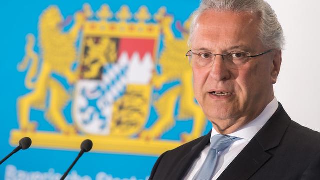 Der bayerische Innenminister Joachim Herrmann, CSU, spricht vor einem Landeswappen