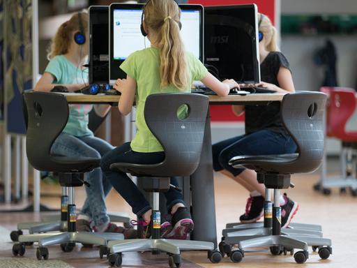 Schülerinnen sitzen an einem Computer-Arbeitsplatz in einer Grundschule.
