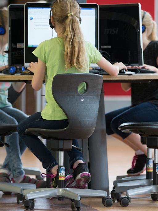 Schülerinnen sitzen an einem Computer-Arbeitsplatz in einer Grundschule.