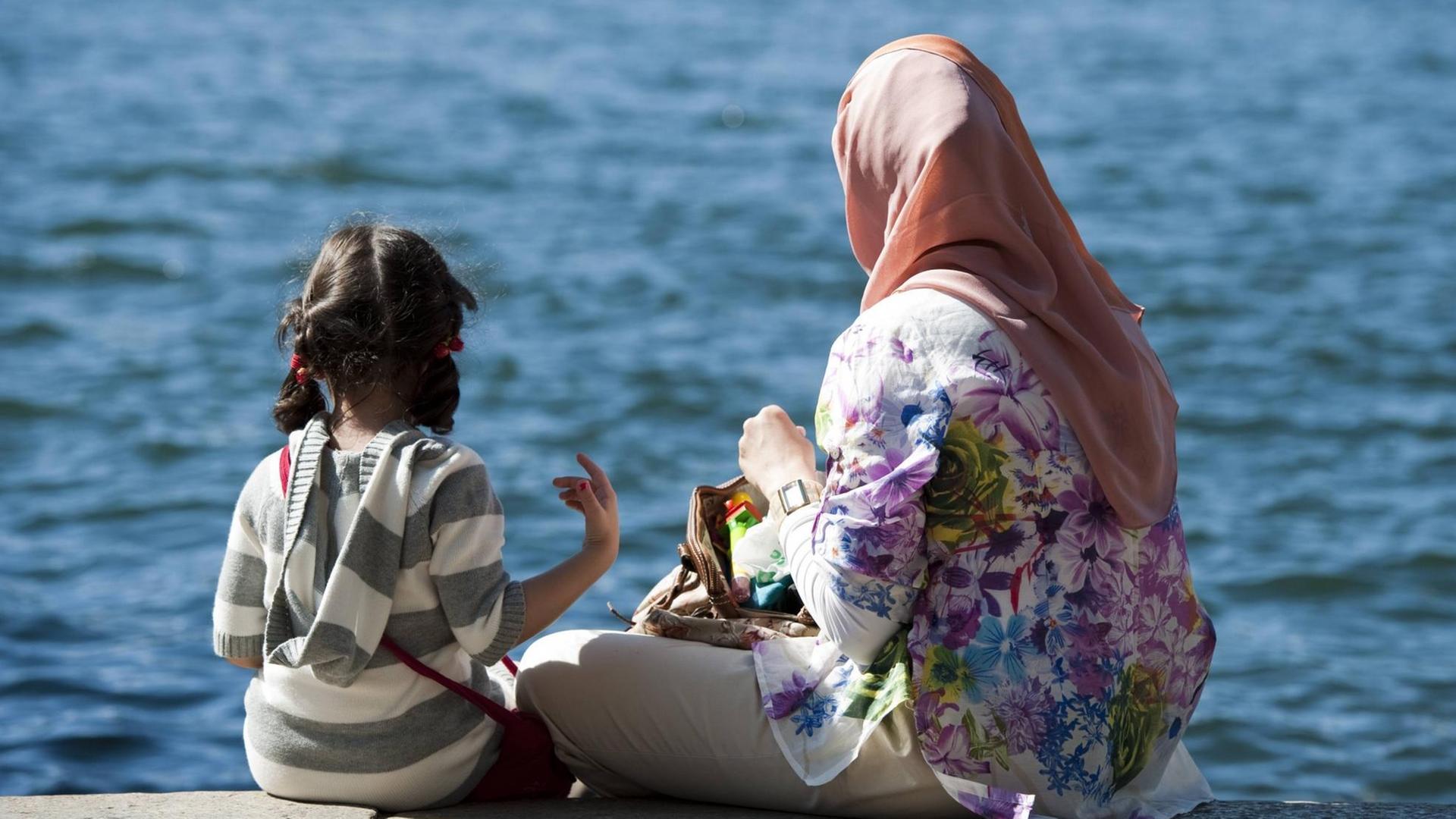 Frau mit Kopftuch und Tochter an einem See. Frau mit Kopftuch und Tochter an einem See.