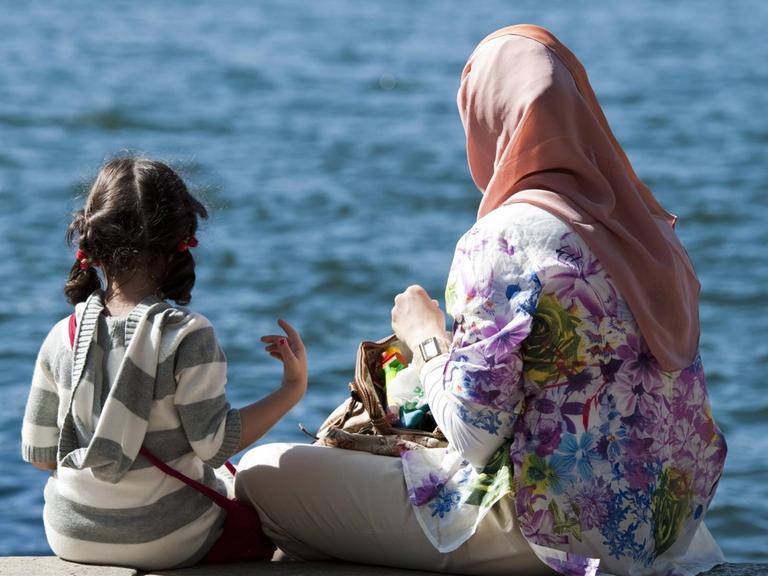 Frau mit Kopftuch und Tochter an einem See.