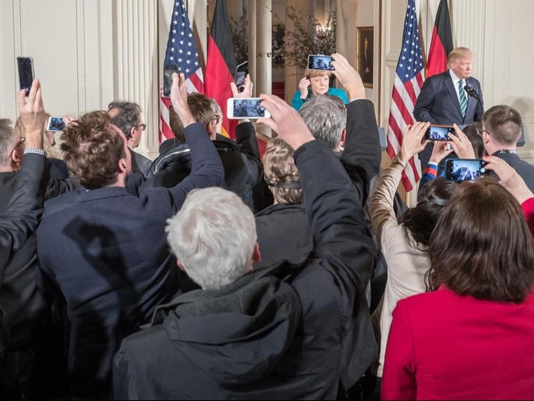 Journalisten fotografieren US-Präsident Donald Trump und Bundeskanzlerin Angela Merkel mit ihren Smartphones.