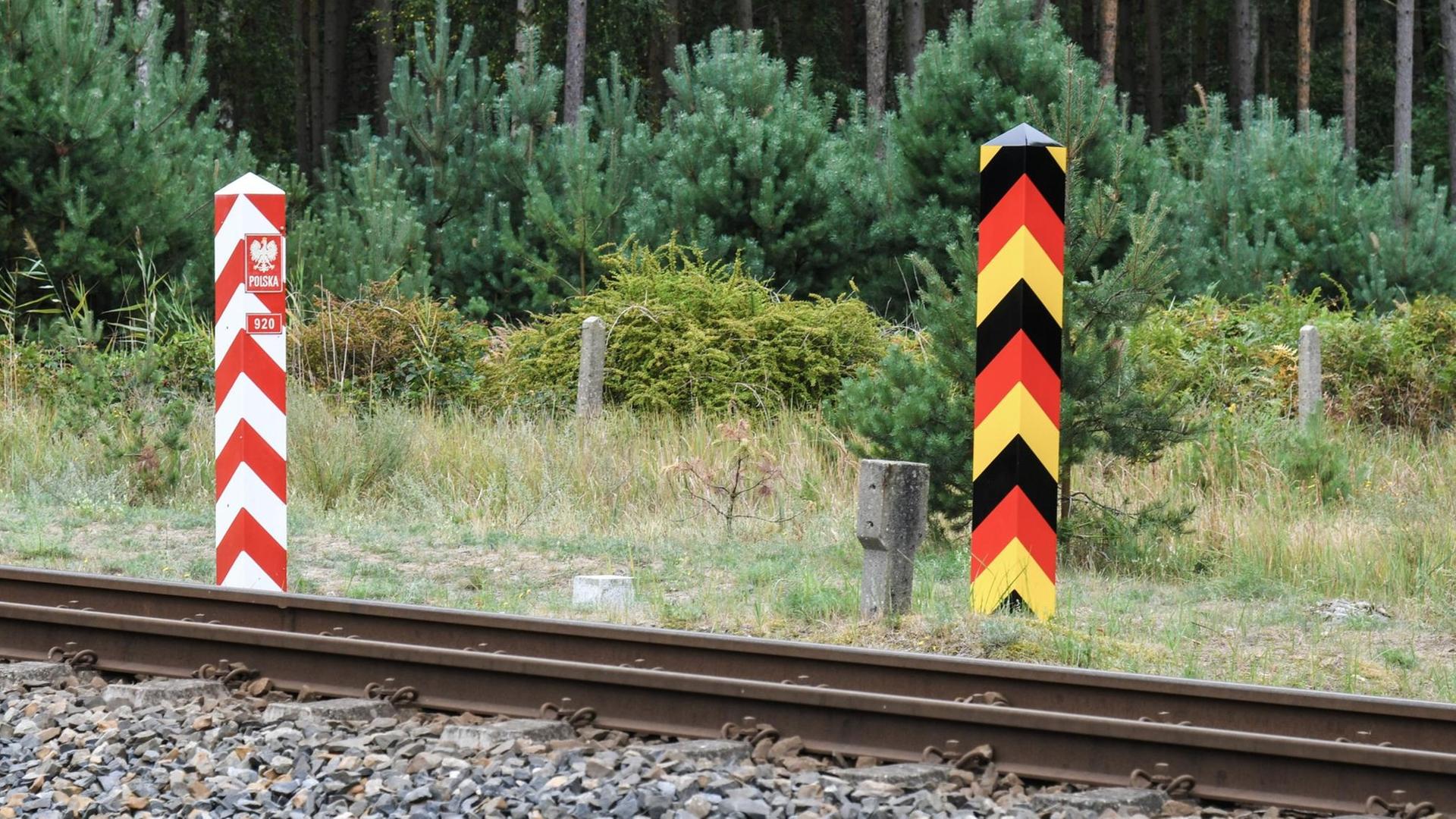 Blick auf zwei Grenzpfosten - einer in den deutschen Farben schwarz-rot-gold und einer in den polnischen Farben rot und weiß. Blick auf zwei Grenzpfosten - einer in den deutschen Farben schwarz-rot-gold und einer in den polnischen Farben rot und weiß.