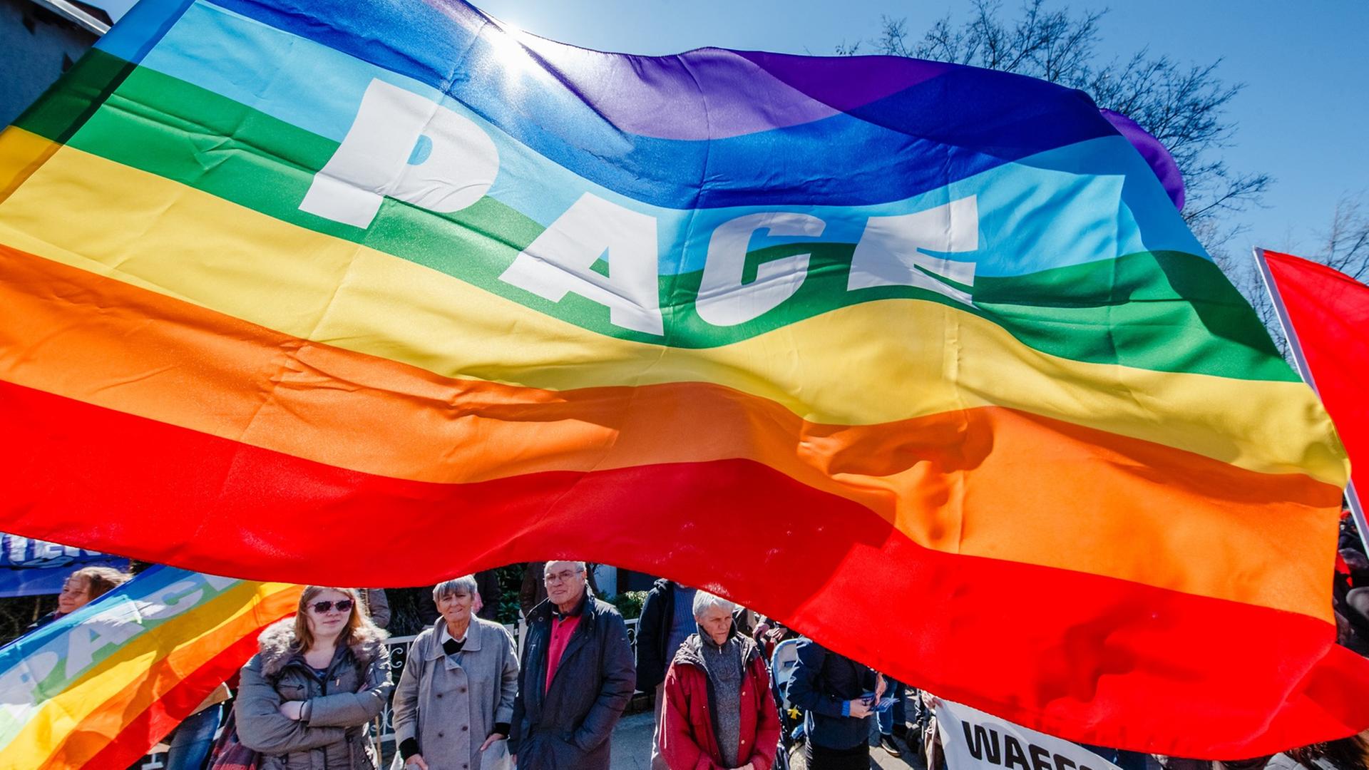 Demonstranten der Friedensbewegung stehen am 06.04.2015 in Hamburg auf dem traditionellen Ostermarsch unter einer Fahne mit der Aufschrift PACE Demonstranten der Friedensbewegung stehen am 06.04.2015 in Hamburg auf dem traditionellen Ostermarsch unter einer Fahne mit der Aufschrift PACE