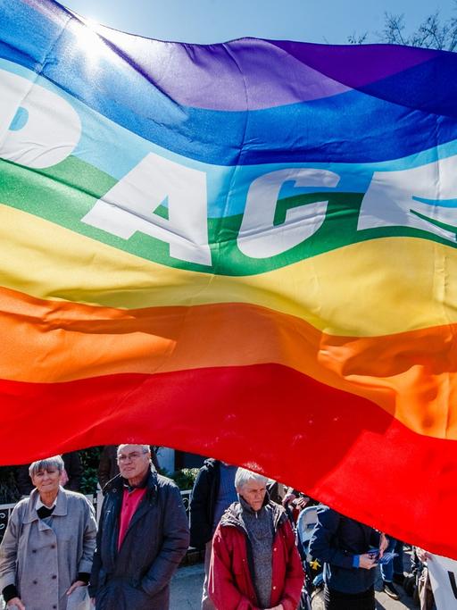 Demonstranten der Friedensbewegung stehen am 06.04.2015 in Hamburg auf dem traditionellen Ostermarsch unter einer Fahne mit der Aufschrift PACE
