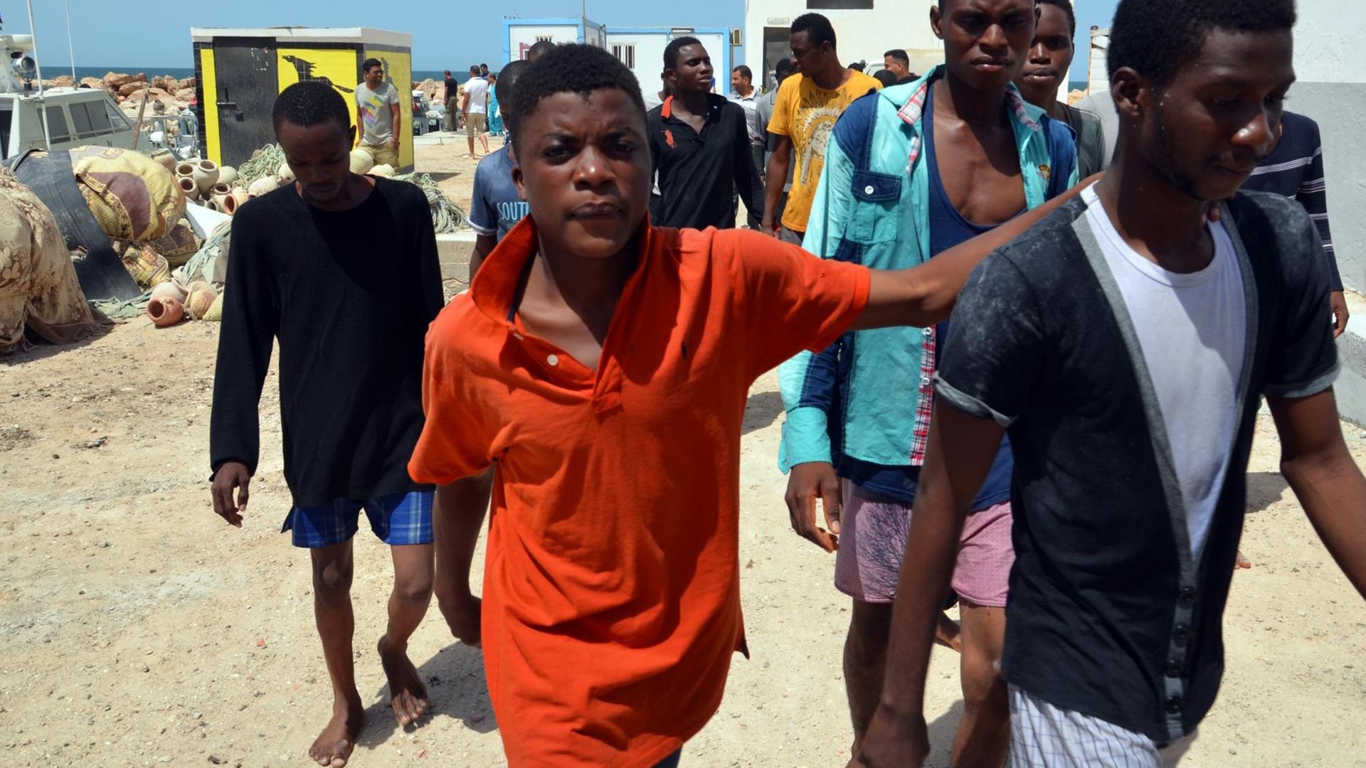 Migranten aus Subsahara-Afrika kommen im Hafen der tunesischen Stadt Ben Guerdane an, nachdem sie von der tunesischen Küstenwache aus dem Mittelmeer vor Libyen gerettet wurden Migranten aus Subsahara-Afrika kommen im Hafen der tunesischen Stadt Ben Guerdane an, nachdem sie von der tunesischen Küstenwache aus dem Mittelmeer vor Libyen gerettet wurden