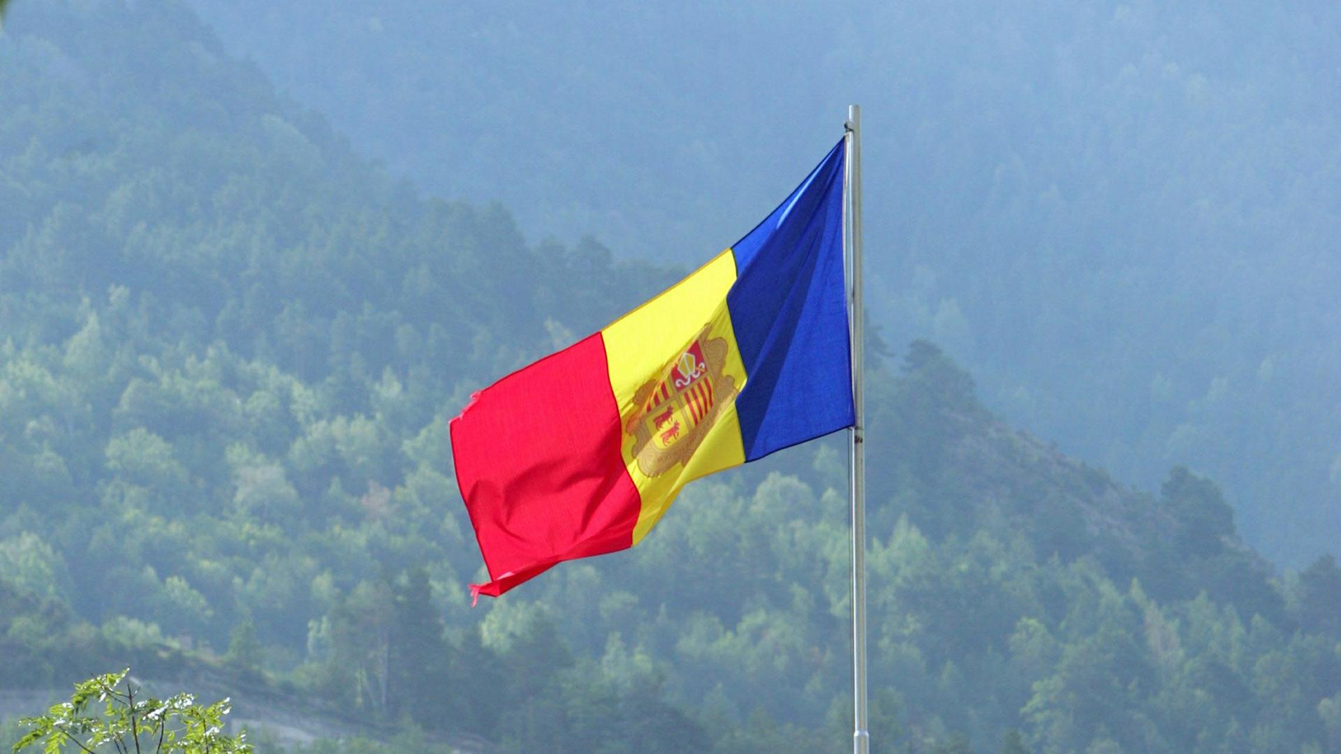 Die Nationalflagge von Andorra, im Hintergrund sind die Pyrenäen zu erkennen. Die Nationalflagge von Andorra, im Hintergrund sind die Pyrenäen zu erkennen.