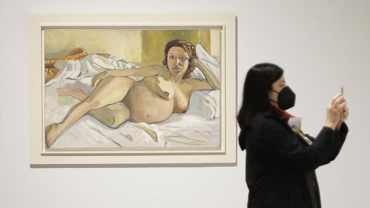 Blick in die Ausstellung. Eine Frau steht neben dem Gemälde "Pregnant Maria" von Alice Neel. Blick in die Ausstellung. Eine Frau steht neben dem Gemälde "Pregnant Maria" von Alice Neel.