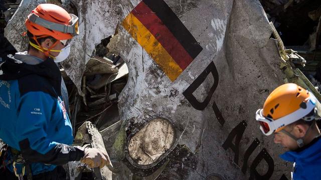 Ein Foto des französischen Innenministeriums zeigt zwei Einsatzkräfte in den französischen Alpen, wie sie ein großes Trümmerteil der abgestürzten Germanwings-Maschine bergen.