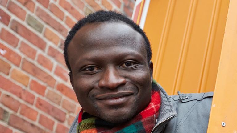 Der Ghanaer Andreas Listowell als Vertreter der "Lampedusa-Flüchtlinge" posiert in Hamburg an der Tür eines Bauwagens mit der Aufschrift "Embassy of Hope".
