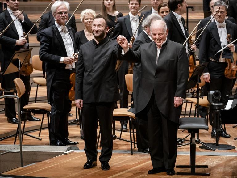 Dirigent und Pianist stehen vor dem Orchester.