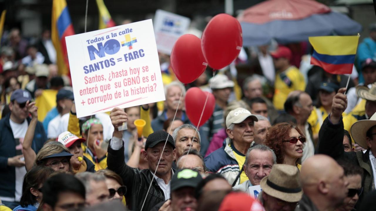 Kritiker des Friedensvertrags und des kolumbianischen Präsidenten Santos halten Protestplakate, Flaggen und rote Luftballons in die Höhe. Kritiker des Friedensvertrags und des kolumbianischen Präsidenten Santos halten Protestplakate, Flaggen und rote Luftballons in die Höhe.