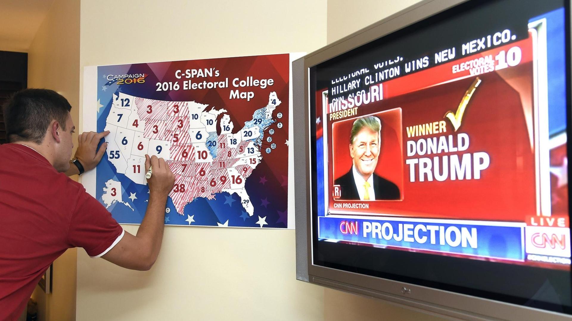 Ein Anhänger Donald Trumps markiert auf einer Tafel die gewonnen Bundesstaaten bei der Präsidentschaftswahl in den USA. Ein Anhänger Donald Trumps markiert auf einer Tafel die gewonnen Bundesstaaten bei der Präsidentschaftswahl in den USA.