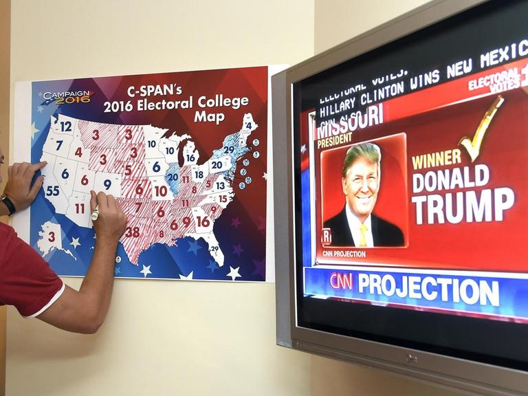 Ein Anhänger Donald Trumps markiert auf einer Tafel die gewonnen Bundesstaaten bei der Präsidentschaftswahl in den USA.