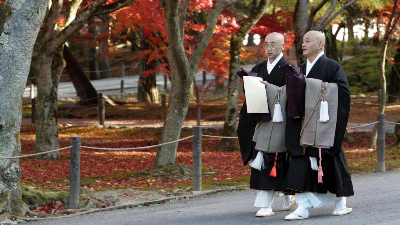 Buddhistische Priester laufen durch einen Garten des Nanzen-ji-Tempels in Kyōto, einem der bekanntesten Tempel des Rinzai-Zen. Buddhistische Priester laufen durch einen Garten des Nanzen-ji-Tempels in Kyōto, einem der bekanntesten Tempel des Rinzai-Zen.