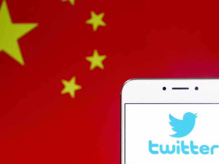 Die Flagge der Volksrepublik China neben dem Logo von Twitter auf einem Smartphone