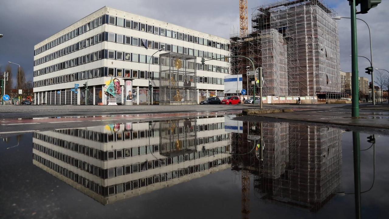 Das Rechenzentrum und die Baustelle für den Wiederaufbau des Turms der Garnisonkirche spiegeln sich in einer Pfütze in Potsdam. Das Rechenzentrum und die Baustelle für den Wiederaufbau des Turms der Garnisonkirche spiegeln sich in einer Pfütze in Potsdam.