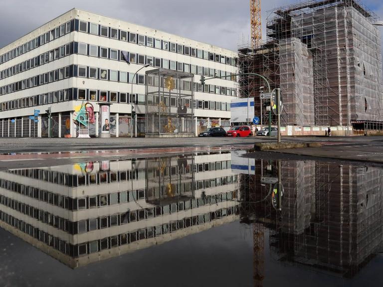 Das Rechenzentrum und die Baustelle für den Wiederaufbau des Turms der Garnisonkirche spiegeln sich in einer Pfütze in Potsdam.