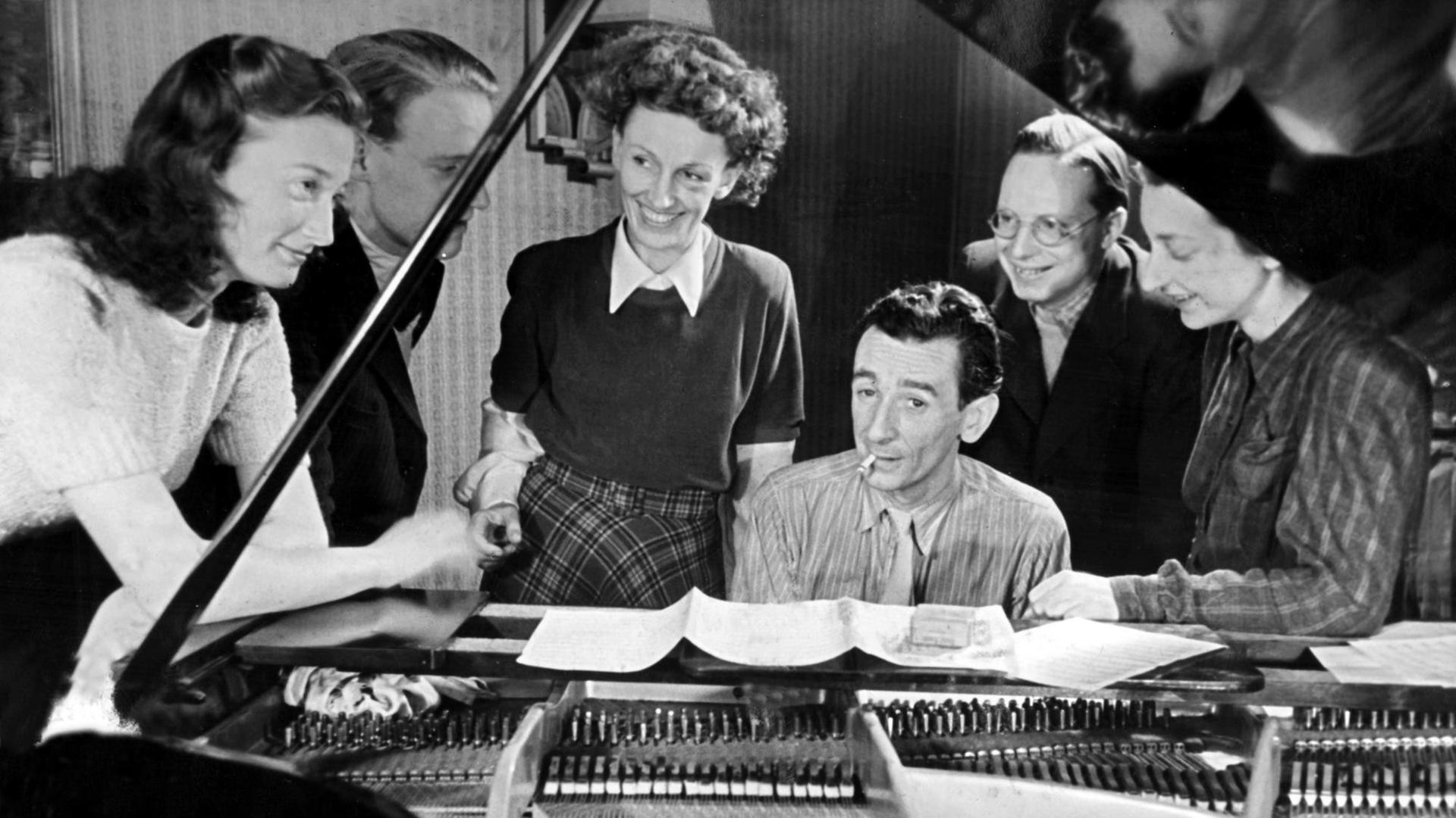 Die Sängerin Lale Andersen steht am Klavier, umringt von den Mitgliedern der Gruppe "Regenpfeifer": Die Stenotypistin Marianne, der Ingenieursstudent Horst, der Pianist Wolfgang, der Musikstudent Theo und die Schauspielschülerin Ursel. Die Sängerin Lale Andersen steht am Klavier, umringt von den Mitgliedern der Gruppe "Regenpfeifer": Die Stenotypistin Marianne, der Ingenieursstudent Horst, der Pianist Wolfgang, der Musikstudent Theo und die Schauspielschülerin Ursel.