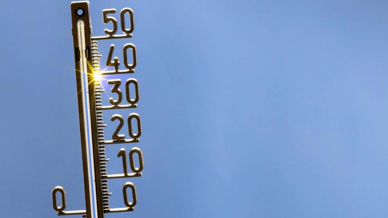 Ein analoges Thermometer vor blauem Himmel zeigt 40 Grad Celsius an. Ein analoges Thermometer vor blauem Himmel zeigt 40 Grad Celsius an.