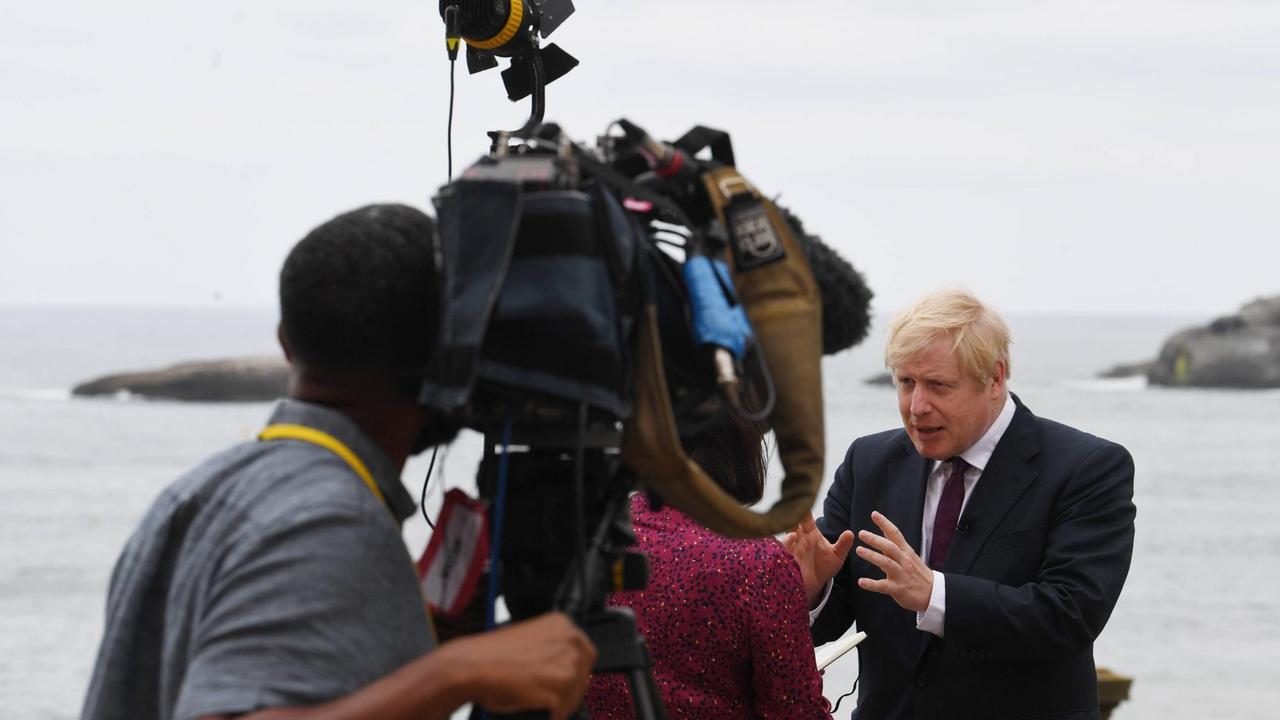 Boris Johnson steht während eines Interviews auf einer Terrasse oberhalb des Meeres und wird von einer Kamera gefilmt. Boris Johnson steht während eines Interviews auf einer Terrasse oberhalb des Meeres und wird von einer Kamera gefilmt.