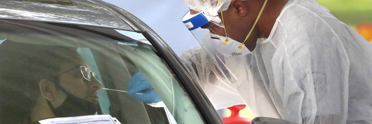 Ein Mann macht einen Coronatest durch ein Autofenster. Ein Mann macht einen Coronatest durch ein Autofenster.