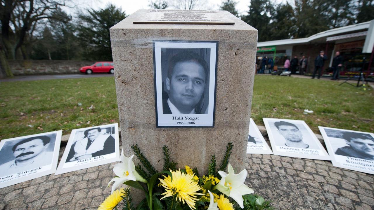 Vor dem Gedenkstein mit einem Foto von Halit Yozgat liegen frische Blumen, dahinter die Fotos der anderen NSU-Opfer.