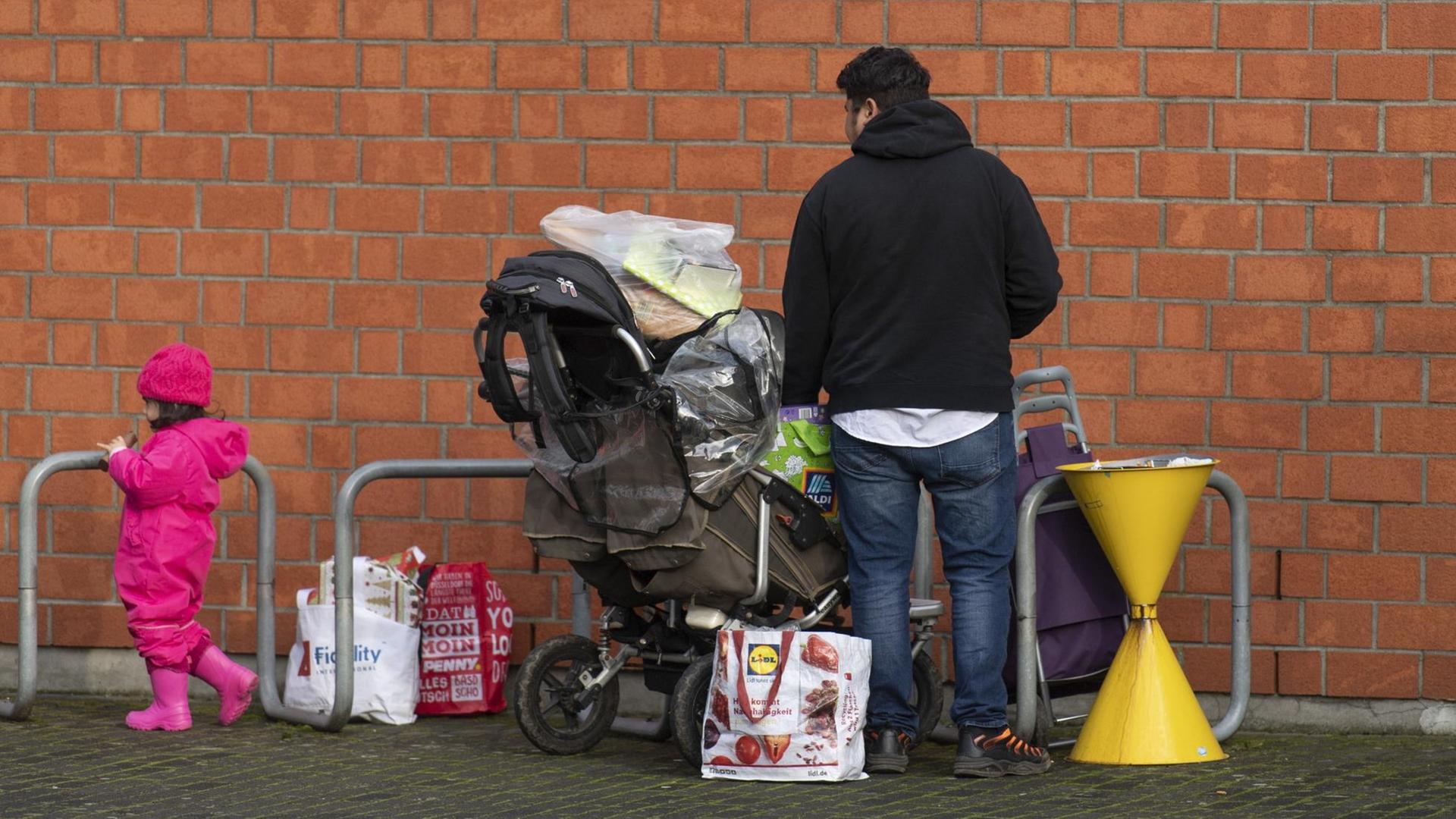Nachdem sie sich bei der Tafel in der Kirche St. Lioba mit Nahrungsmitteln versorgt haben stehen ein Mann und ein kleines Kind mit vollgepackten Tüten im Freien. Zu den Kunden der Tafeln gehören neben Rentnern auch ganze Familien und alleinstehende Frauen mit ihren Kindern. Nachdem sie sich bei der Tafel in der Kirche St. Lioba mit Nahrungsmitteln versorgt haben stehen ein Mann und ein kleines Kind mit vollgepackten Tüten im Freien. Zu den Kunden der Tafeln gehören neben Rentnern auch ganze Familien und alleinstehende Frauen mit ihren Kindern.