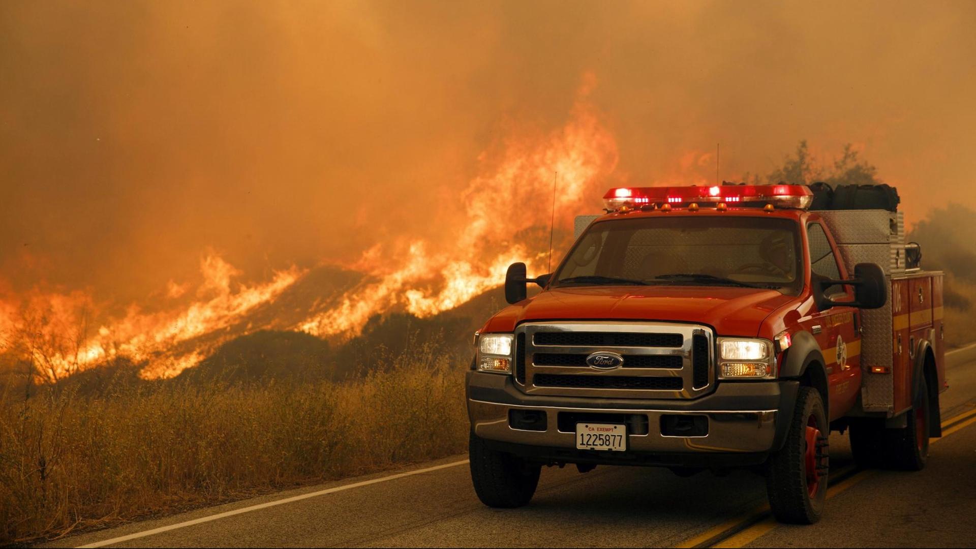 Ein Feuerwehrfahrzeug steht währende eines Waldbrands auf einer Straße in Santa Clarita, California.