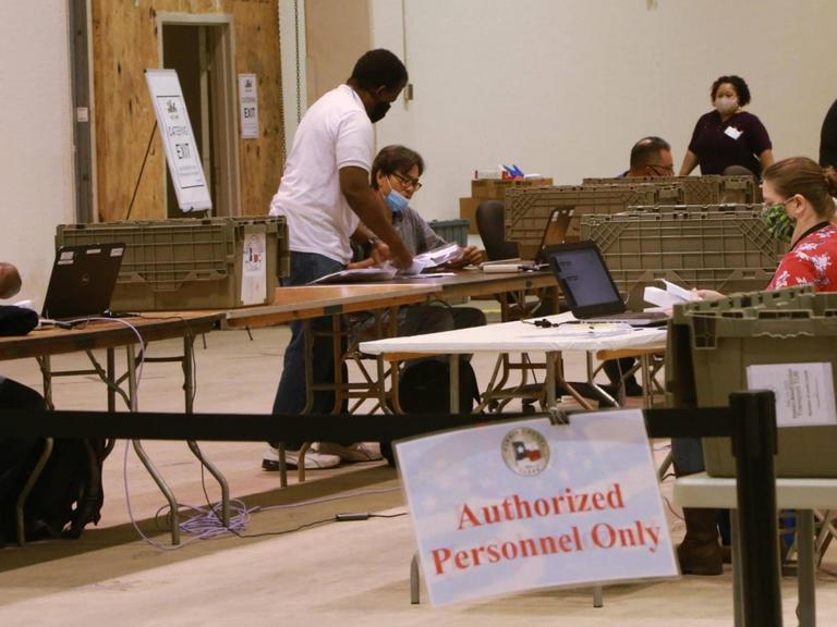 Wahlhelfer bei der Stimmenauszählung zu den US-Wahlen 2020 in Harris, Texas. Sie sitzen an Tischen und zählen die abgegeben Stimmen.