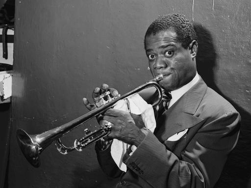 Eine historische Schwarz-Weiß-Aufnahme von Louis Armstrong mit seiner Trompete im Jazzclub Aquarium in New York City im Juli 1946.