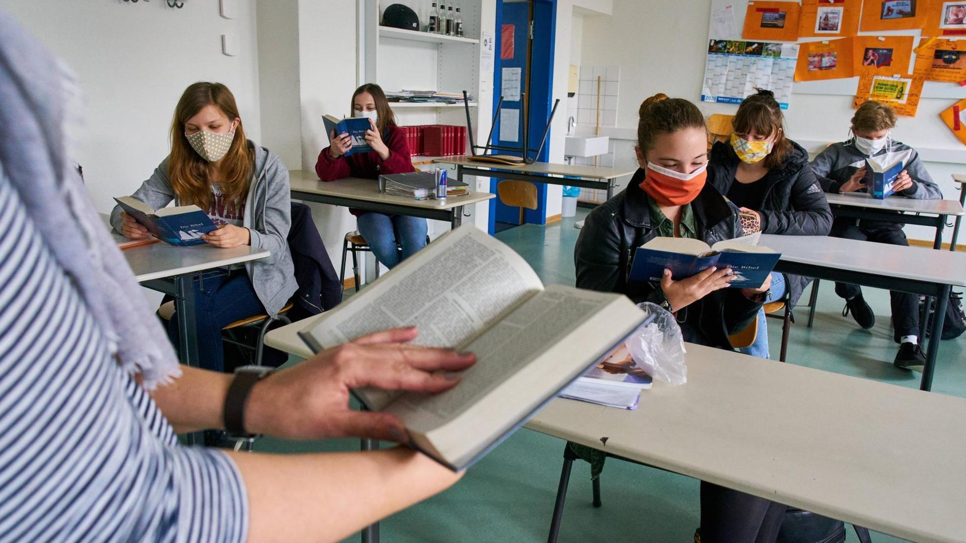 Schülerinnen und Schüler mit Masken sitzen an ihren Tischen im Klassenraum und lesen im Unterricht in Marktoberdorf im 27. April 2020. Schülerinnen und Schüler mit Masken sitzen an ihren Tischen im Klassenraum und lesen im Unterricht in Marktoberdorf im 27. April 2020.