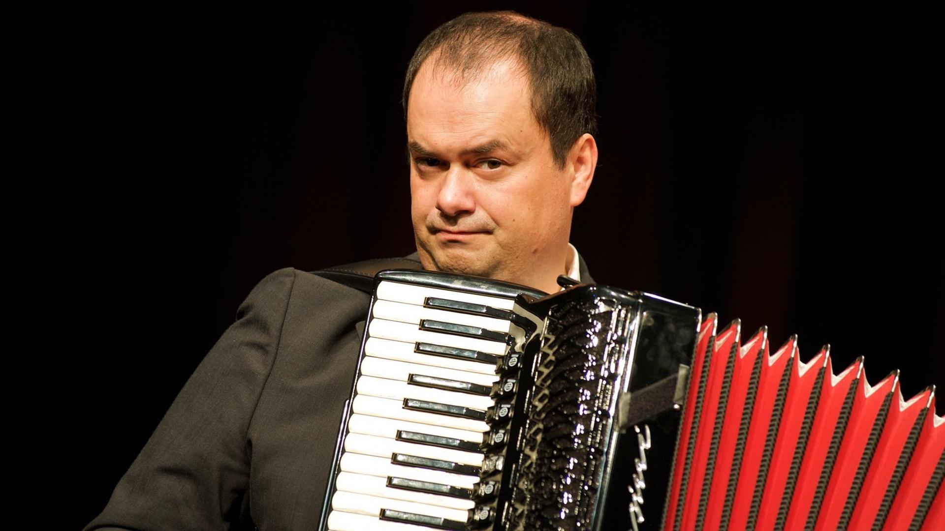 Der Musikkabarettist Frank Grischek steht mit seinem Akkordeon auf der Bühne. Der Musikkabarettist Frank Grischek steht mit seinem Akkordeon auf der Bühne.