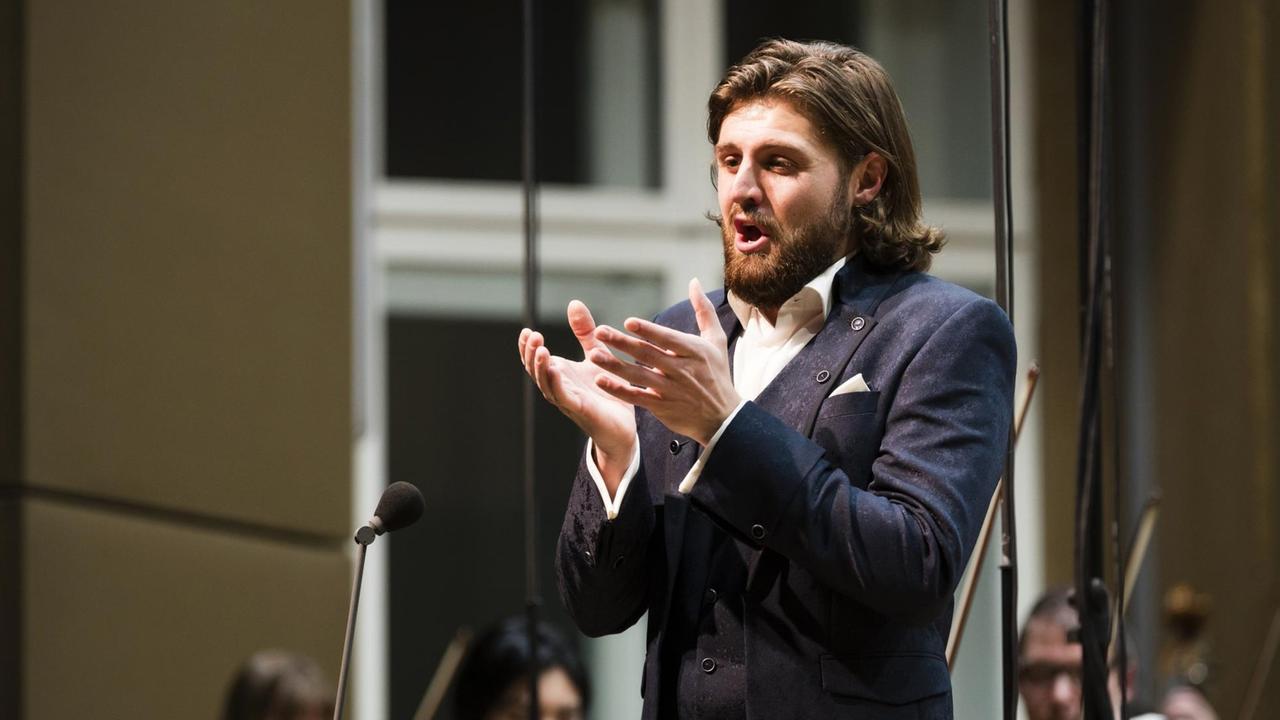 Der Bariton singt auf der Bühne mit Orchester Der Bariton singt auf der Bühne mit Orchester