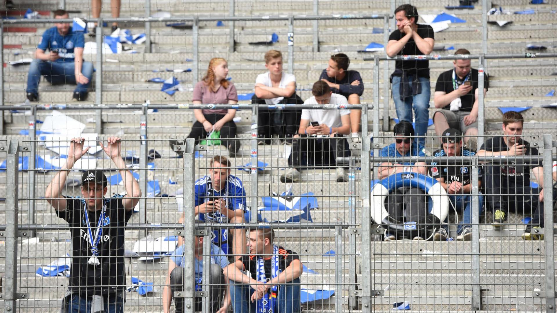 12.05.2018, Hamburg. Fußball: Bundesliga, 34. Spieltag, Hamburger SV - Borussia Mönchengladbach im Volksparkstadion. Fans von Hamburg sitzen nach Spielende traurig auf der halbleeren Tribüne. Der Hamburger SV steigt erstmals in seiner Vereinsgeschichte aus der Fußball-Bundesliga ab. Foto: Daniel Bockwoldt/dpa | Verwendung weltweit 12.05.2018, Hamburg. Fußball: Bundesliga, 34. Spieltag, Hamburger SV - Borussia Mönchengladbach im Volksparkstadion. Fans von Hamburg sitzen nach Spielende traurig auf der halbleeren Tribüne. Der Hamburger SV steigt erstmals in seiner Vereinsgeschichte aus der Fußball-Bundesliga ab. Foto: Daniel Bockwoldt/dpa | Verwendung weltweit