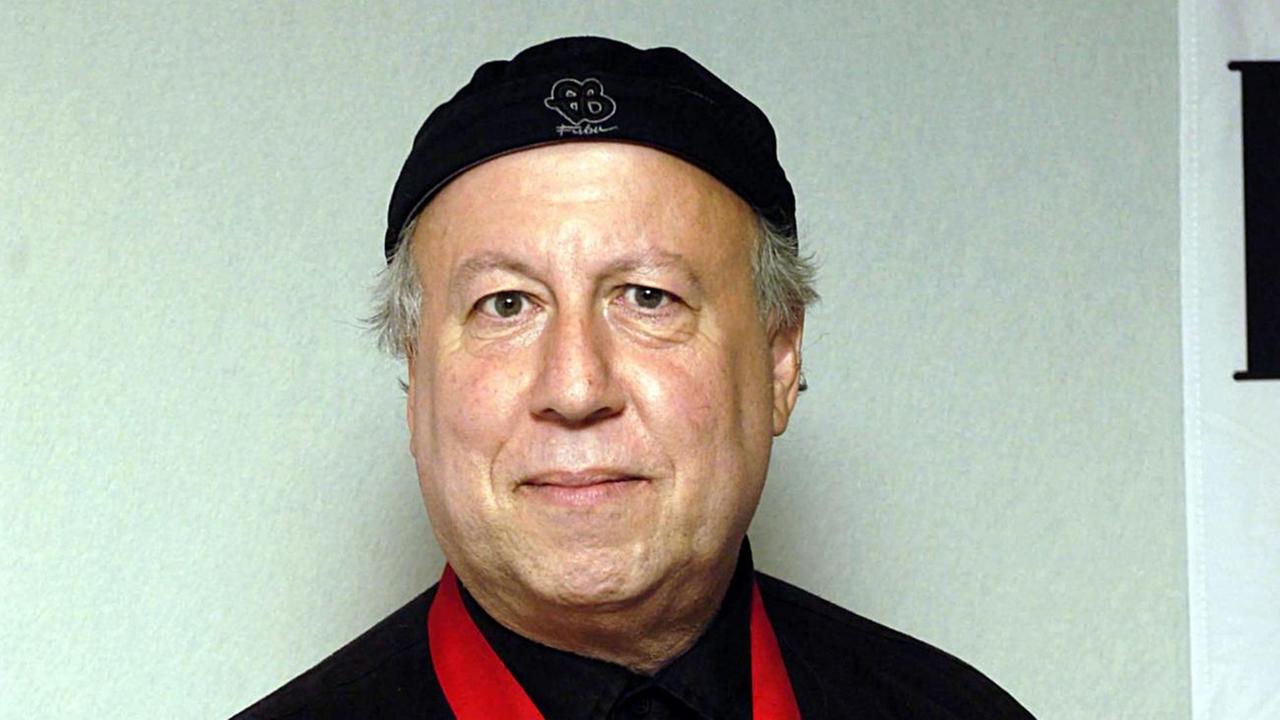 Ein schwarzgekleideter Mann steht vor einer hellen Wand Ein schwarzgekleideter Mann steht vor einer hellen Wand