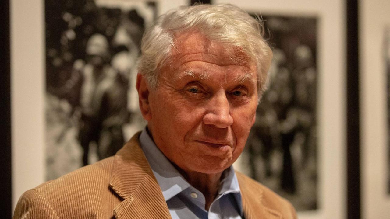Der britische Fotograf Don McCullin steht lächelnd vor seinen schwarz-weiß Fotografien, Der britische Fotograf Don McCullin steht lächelnd vor seinen schwarz-weiß Fotografien,