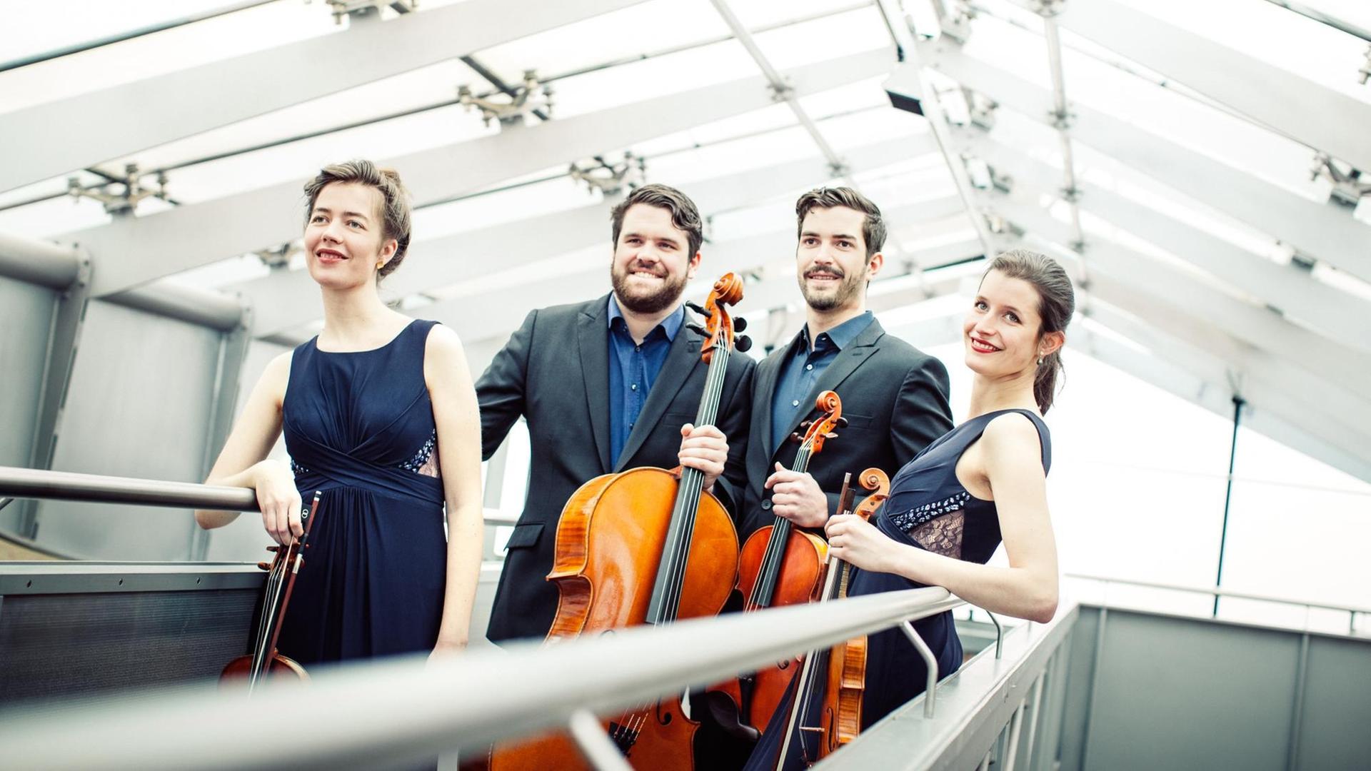 Die vier Musiker des Aris Quartett stehen unter einem Glasdach auf einer Rampe und halten die Instrumente in ihren Händen. Die vier Musiker des Aris Quartett stehen unter einem Glasdach auf einer Rampe und halten die Instrumente in ihren Händen.