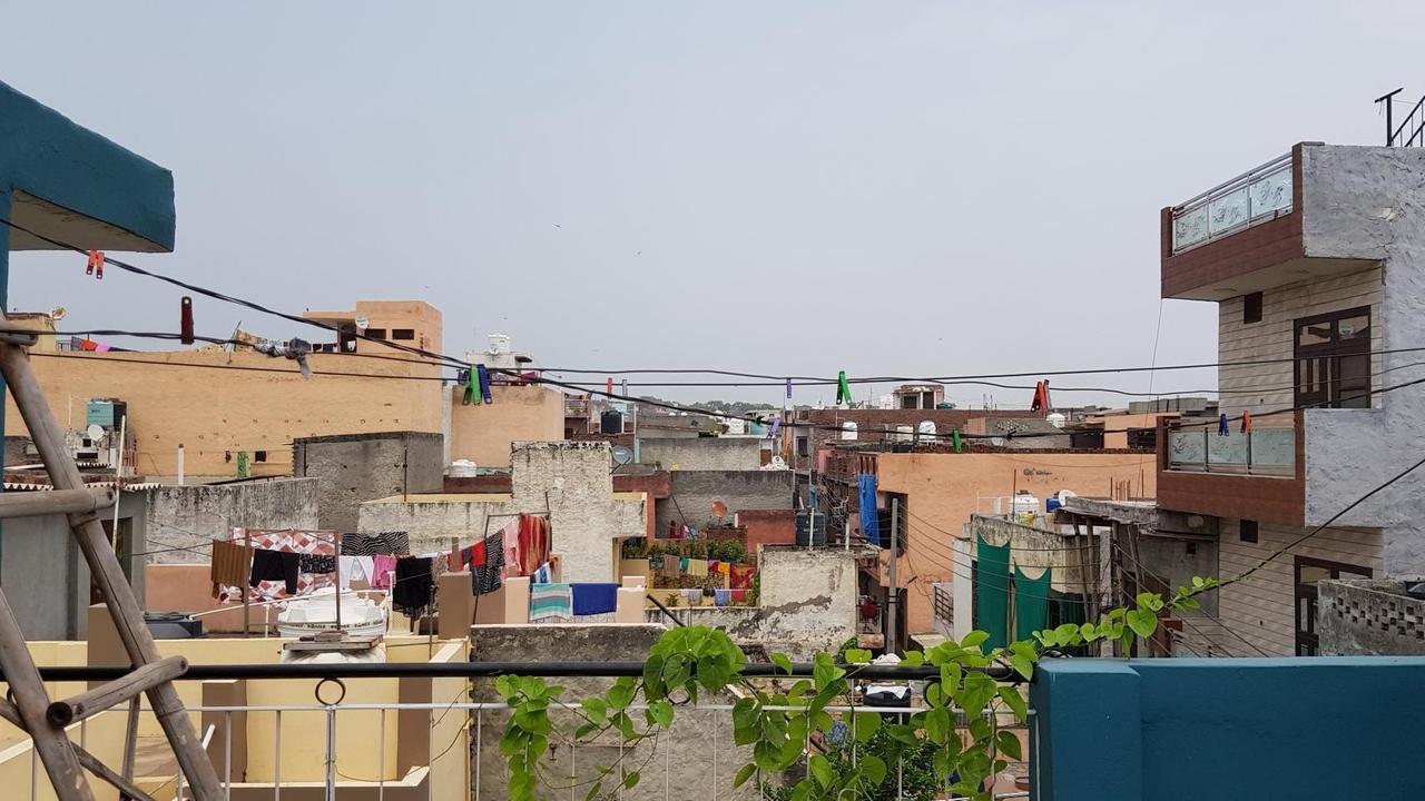 Blick über viele niedrige und flache Dächer einer Ortschaft vom Balkon aus. Überall hängt bunte Wäsche draußen.