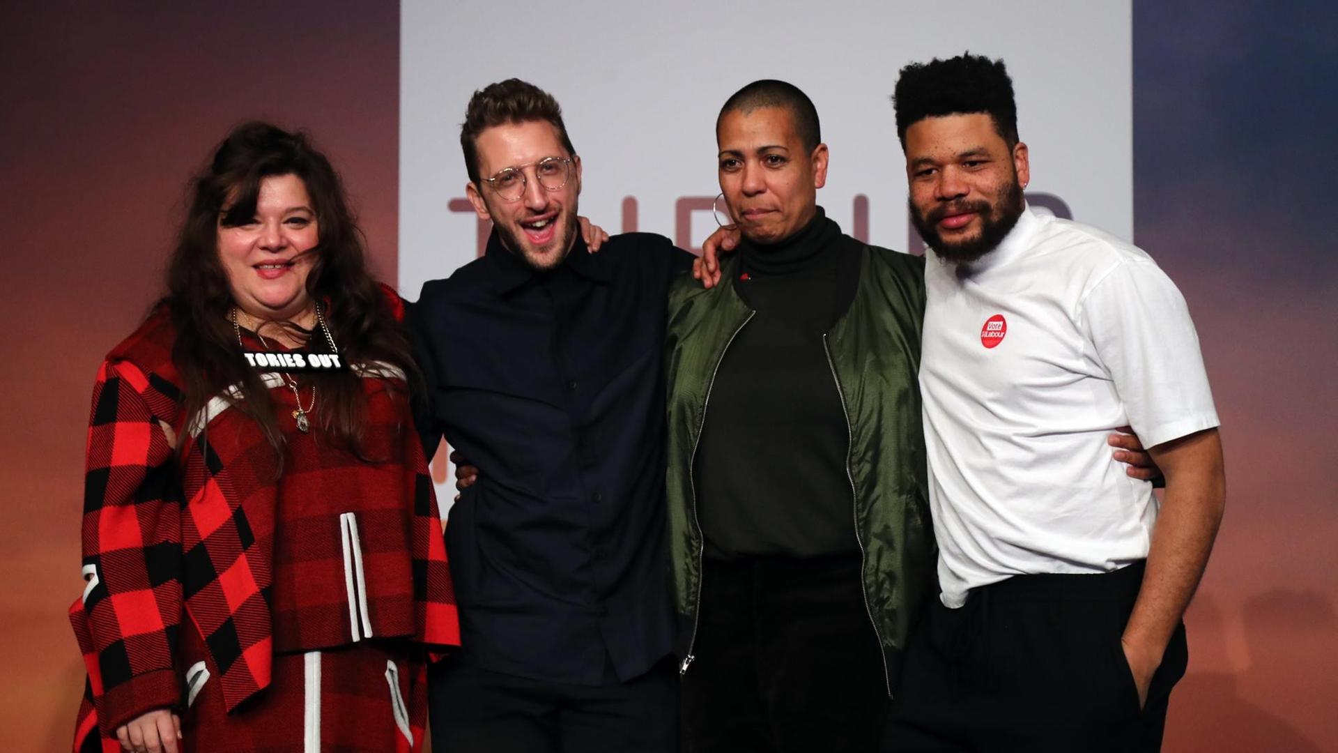 Die Künstler Tai Shani, Lawrence Abu Hamdan, Helen Cammock und Oscar Murillo stehen auf der Bühne und lächeln in die Kamera. Die Künstler Tai Shani, Lawrence Abu Hamdan, Helen Cammock und Oscar Murillo stehen auf der Bühne und lächeln in die Kamera.