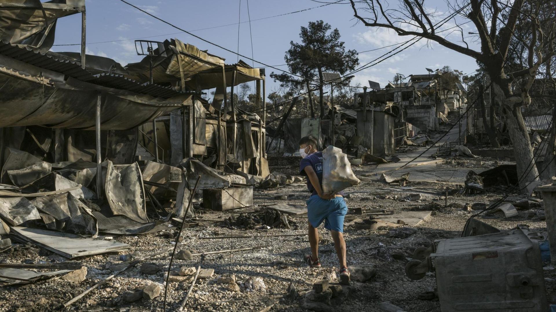 Ein Geflüchteter aus Afghanistan trägt einen Teil seiner Habseligkeiten durch das zerstörte Lager Moria auf Lesbos in Griechenland, 12. September 2020. Ein Geflüchteter aus Afghanistan trägt einen Teil seiner Habseligkeiten durch das zerstörte Lager Moria auf Lesbos in Griechenland, 12. September 2020.